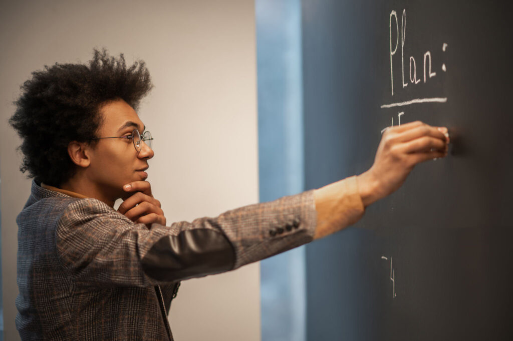 Business planning. Curly-haired businessman doing business planning and writing on the board